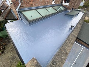 Repaired flat roof with grey resin-based fibre reinforced seamless membrane after laying Rooflock to the splits in asphalt
