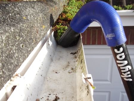 SkyVac gutter clearing vacuum with wireless inspection camera system being used to clean gutter debris including moss, leaves, bird mess and turf